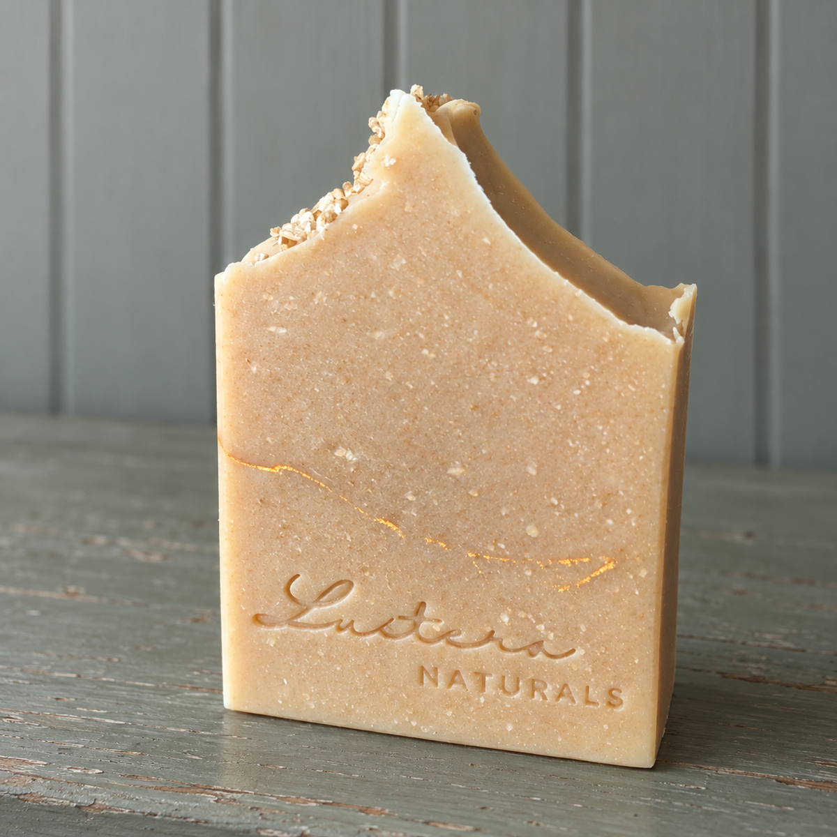 Cream Haven oat-speckled soap bar on muted sage painted wood