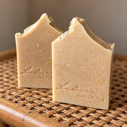 Two Cream Haven goat milk and colloidal oatmeal soap bars on woven cane