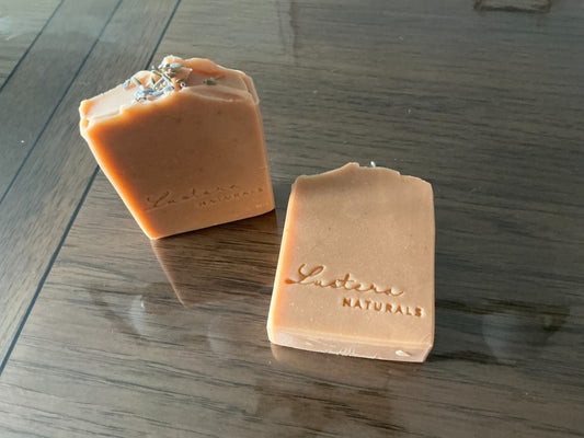 One standing and one flat handmade Lavender soap bar with Lustera Naturals stamps and a dried lavender topping