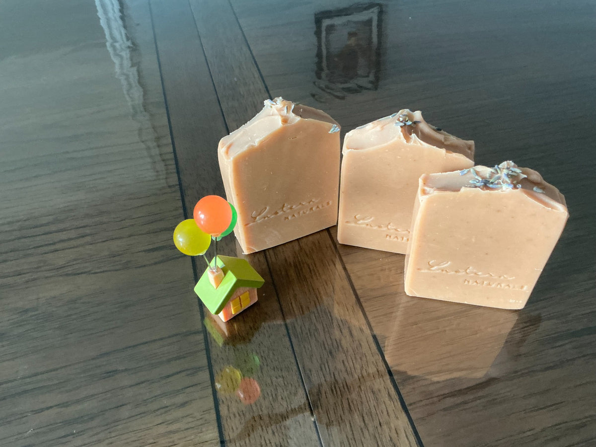 Angled view of three handmade Lavender soap bars showing dried lavender buds, sculpted tops and stamped fronts
