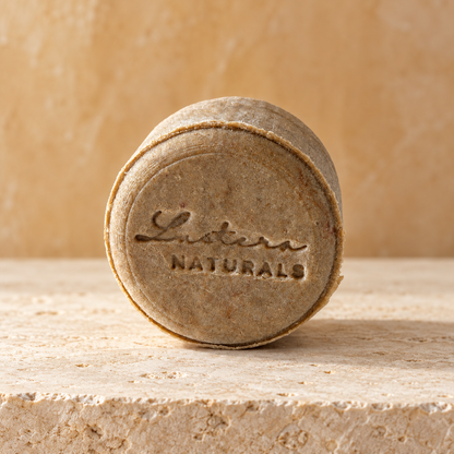 Scalp Sanctuary herbal shampoo bar on a pale limestone ledge
